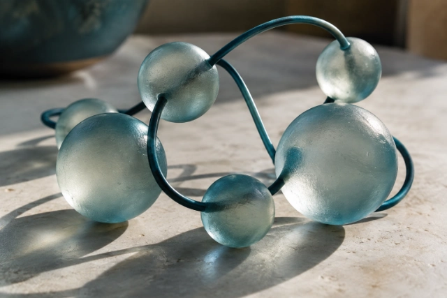 Sculpture de sphères de verre reliées par des tiges métalliques bleu canard